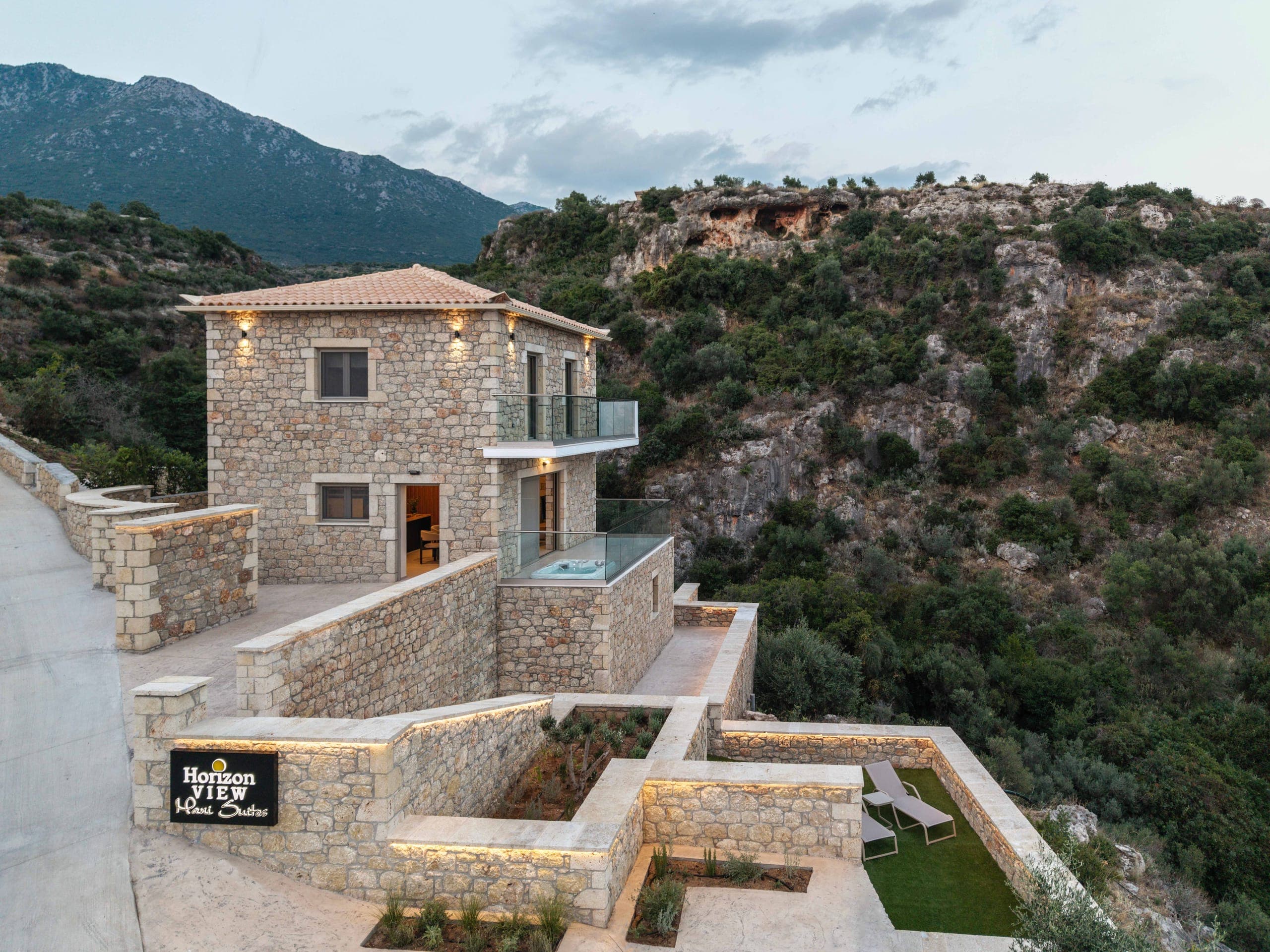 Η πετρόχτιστη κατοικία φωτισμένη το σούρουπο, πάνω από τη ρεματιά